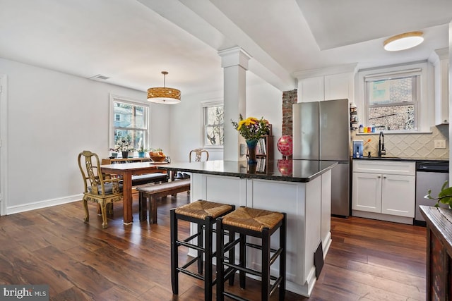 kitchen with dark wood-style floors, visible vents, appliances with stainless steel finishes, dark countertops, and backsplash