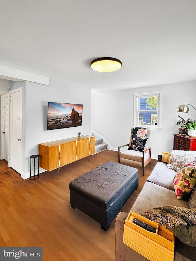 living room featuring stairway, baseboards, and wood finished floors