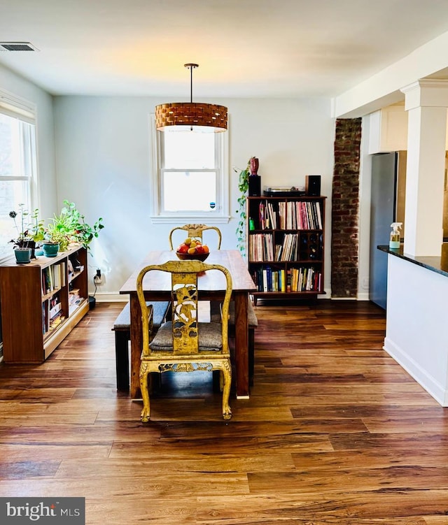 dining room with visible vents, a healthy amount of sunlight, and wood finished floors