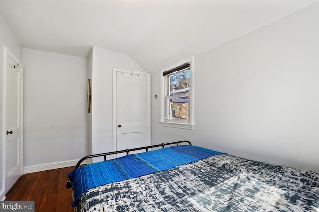 bedroom with a closet, vaulted ceiling, baseboards, and hardwood / wood-style floors