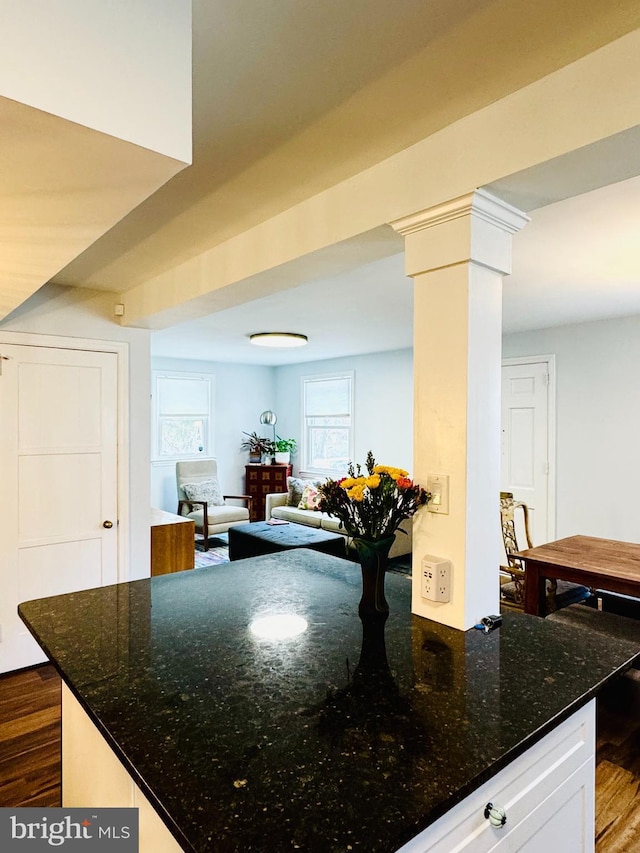 kitchen with dark wood-style floors, white cabinets, ornate columns, and dark stone countertops