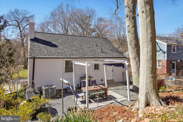 back of house featuring central air condition unit, a patio area, roof with shingles, and a chimney