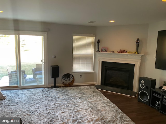 living area featuring visible vents, a fireplace with flush hearth, dark wood finished floors, and recessed lighting