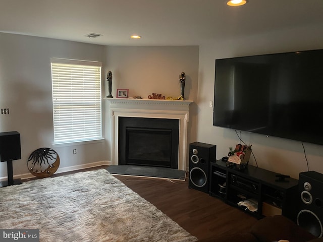 living room with a glass covered fireplace, visible vents, recessed lighting, and wood finished floors