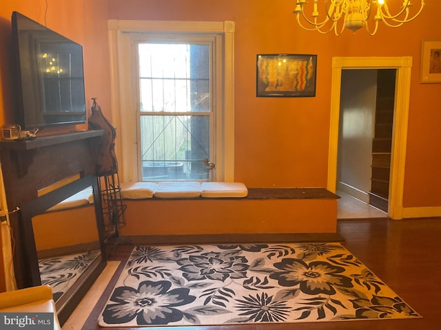 living area featuring baseboards, a notable chandelier, and wood finished floors