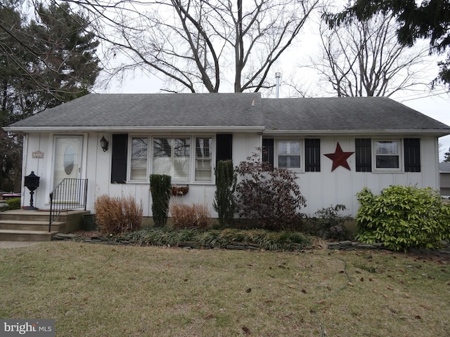 single story home featuring a shingled roof, board and batten siding, and a front yard