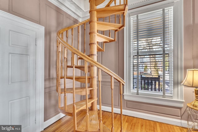 stairway featuring a decorative wall and wood finished floors