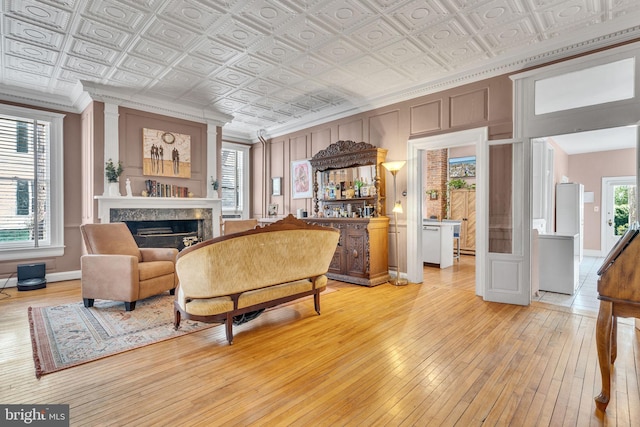 living area featuring an ornate ceiling, a fireplace, and light wood finished floors