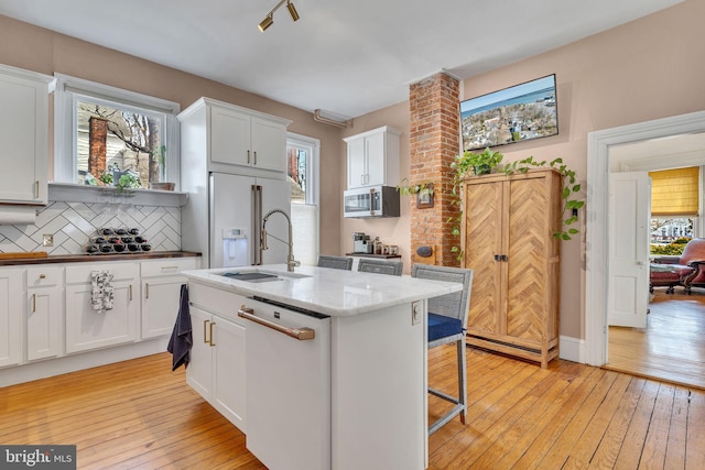 kitchen with light wood finished floors, white appliances, white cabinets, and tasteful backsplash