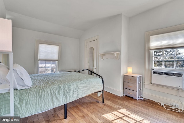 bedroom with baseboards, vaulted ceiling, and hardwood / wood-style floors