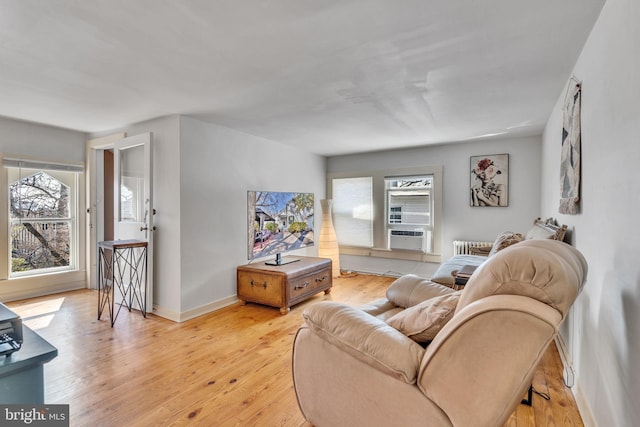 living area with light wood finished floors, baseboards, and cooling unit