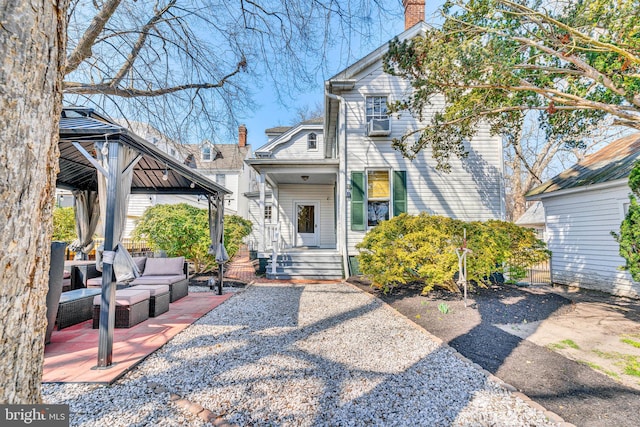 exterior space featuring a chimney, outdoor lounge area, and a gazebo