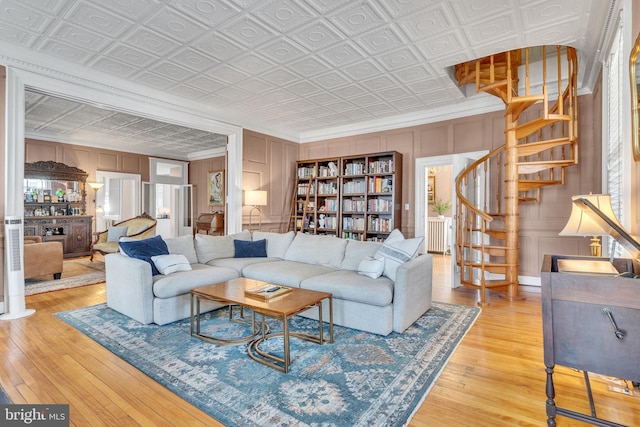 living area with light wood finished floors, an ornate ceiling, stairs, crown molding, and a decorative wall