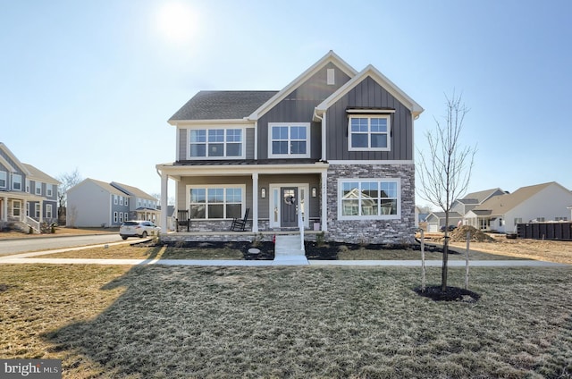 craftsman-style home featuring stone siding, a residential view, a front lawn, and board and batten siding