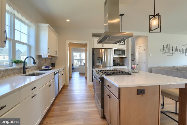 kitchen featuring light wood-style flooring, island range hood, stainless steel appliances, a sink, and decorative backsplash