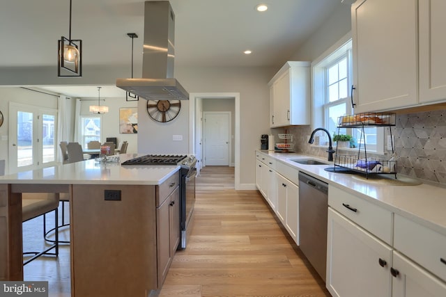 kitchen with light wood-style flooring, island range hood, a sink, a kitchen breakfast bar, and appliances with stainless steel finishes