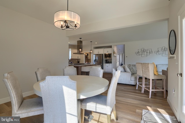 dining room featuring a notable chandelier, light wood finished floors, and baseboards