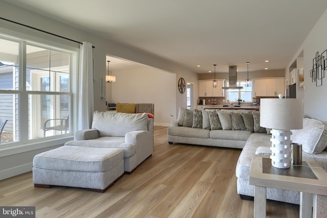 living room featuring a healthy amount of sunlight, light wood-style flooring, and baseboards