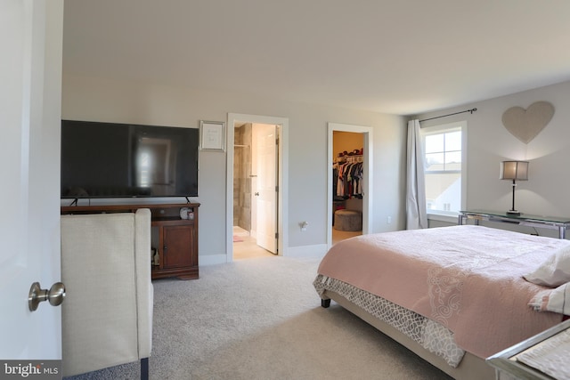 bedroom with carpet flooring, baseboards, a closet, a walk in closet, and ensuite bath