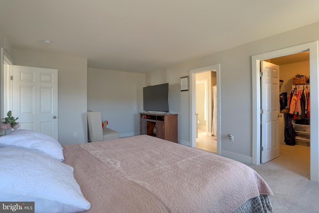 bedroom with ensuite bath, a closet, a walk in closet, and carpet flooring