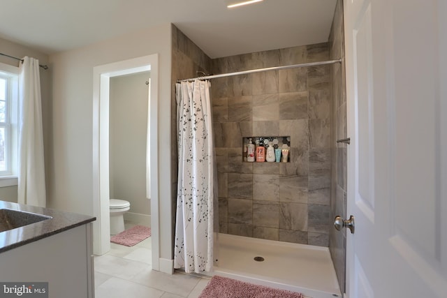 bathroom featuring toilet, tile patterned flooring, tiled shower, and vanity