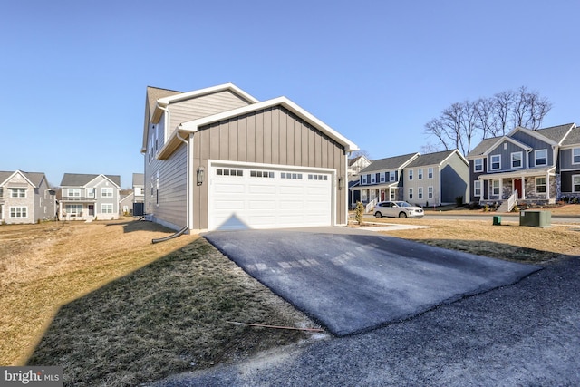 view of front of property featuring aphalt driveway, a residential view, board and batten siding, and an attached garage