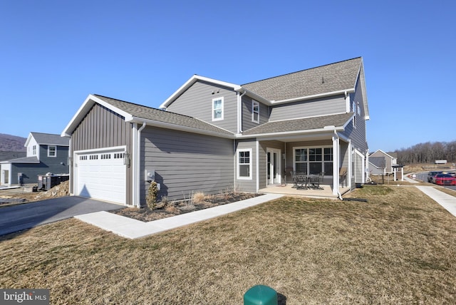 view of front facade featuring a front lawn, a shingled roof, and an attached garage