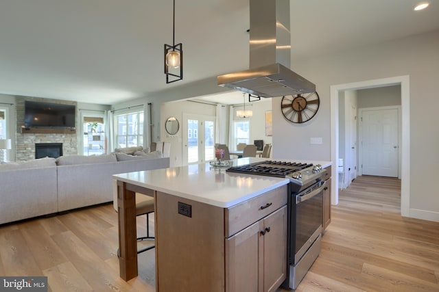 kitchen with light wood finished floors, stainless steel gas range oven, island exhaust hood, and open floor plan