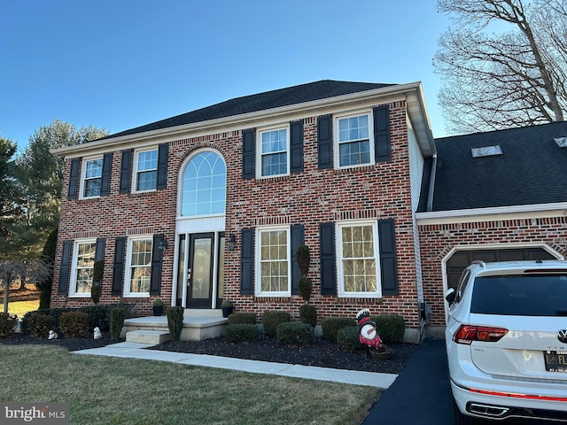 view of front of house featuring brick siding, a front yard, and a shingled roof