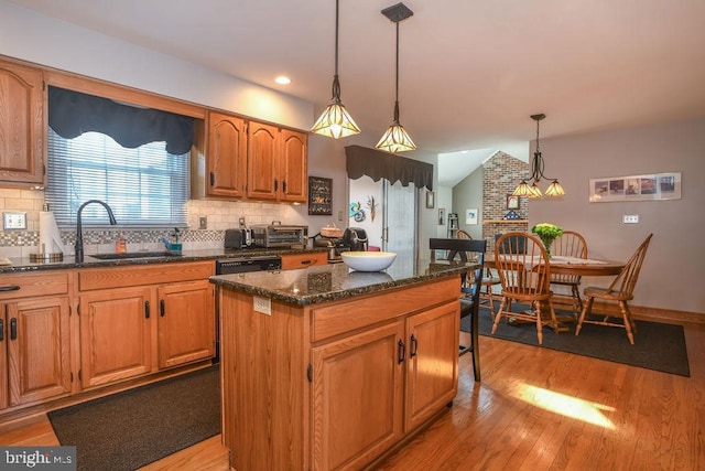 kitchen featuring backsplash, a center island, light wood-style floors, and a sink