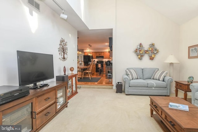 living room with visible vents, light colored carpet, and a towering ceiling