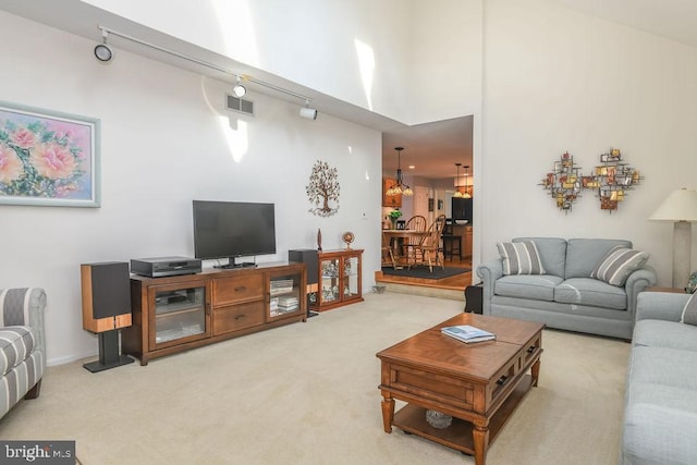 living room featuring carpet, visible vents, and a towering ceiling