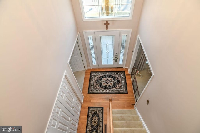 entryway featuring stairs, a high ceiling, wood finished floors, and baseboards