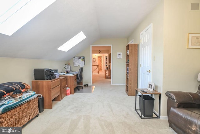 home office with visible vents, vaulted ceiling with skylight, light colored carpet, and baseboards