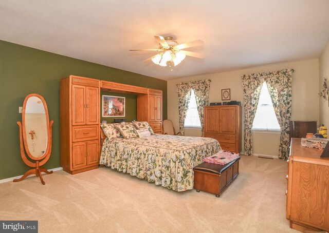 bedroom with light colored carpet, a ceiling fan, and baseboards