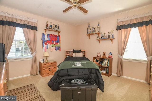 bedroom with a ceiling fan, baseboards, and light carpet