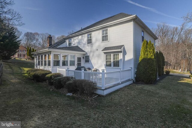 rear view of house featuring a lawn, a chimney, and a deck