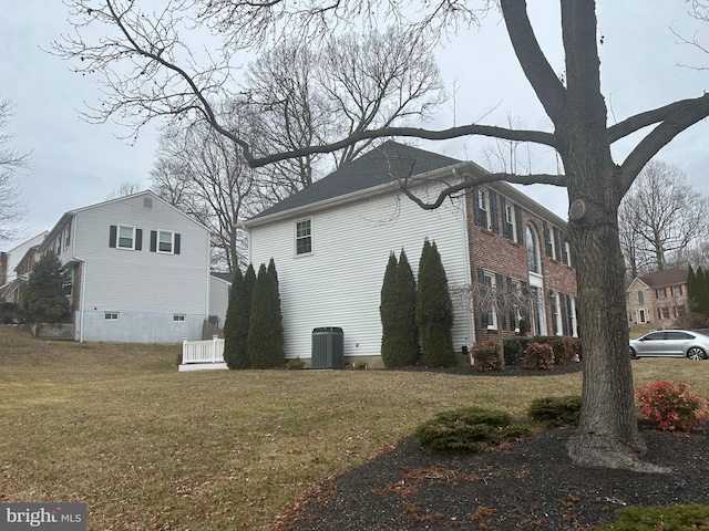 view of side of home featuring a lawn and central AC