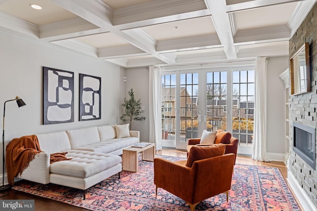 living room featuring light wood finished floors, a fireplace, coffered ceiling, and beamed ceiling