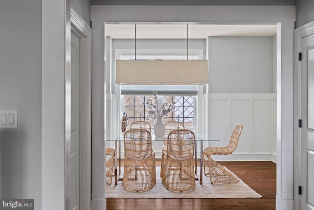 dining room with wainscoting, a decorative wall, and wood finished floors