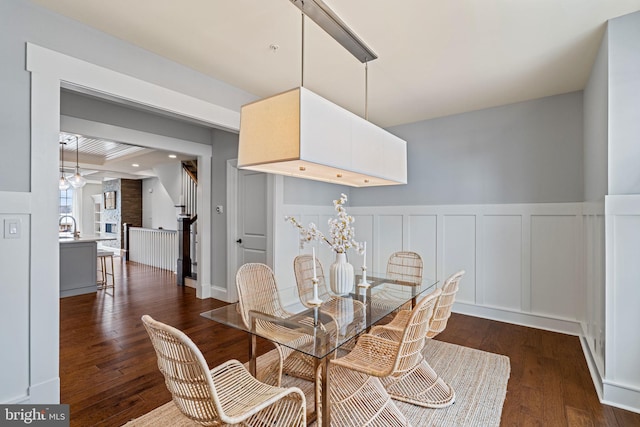 dining area with recessed lighting, dark wood-style flooring, wainscoting, and a decorative wall