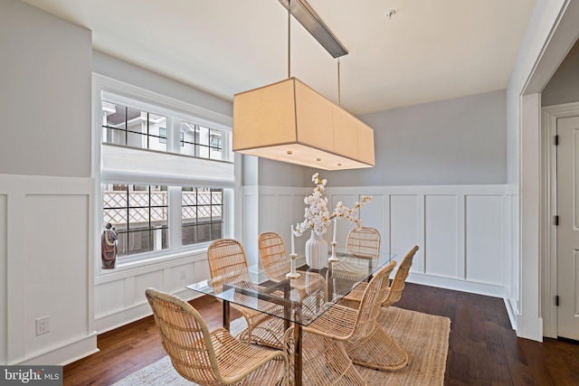 dining space featuring wainscoting, a decorative wall, and wood finished floors