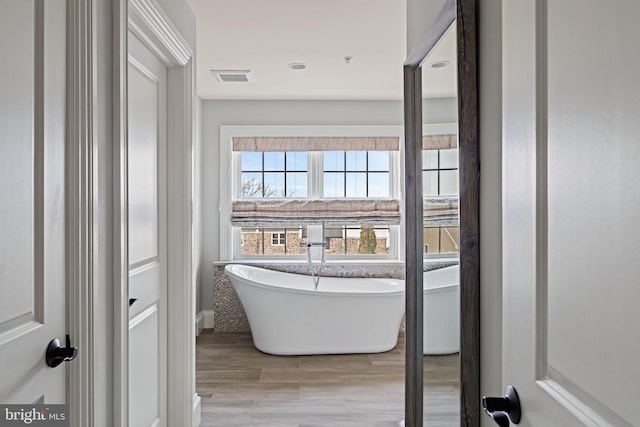 bathroom featuring a freestanding tub, visible vents, and wood finish floors