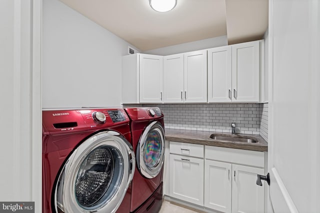 laundry area with cabinet space, washer and clothes dryer, and a sink