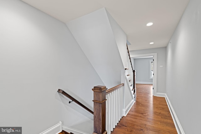 hallway featuring an upstairs landing, baseboards, wood finished floors, and recessed lighting