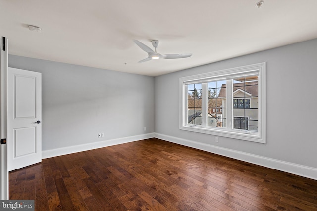 empty room with ceiling fan, dark wood-type flooring, and baseboards