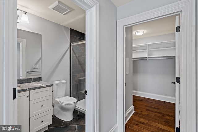 bathroom with toilet, wood finished floors, vanity, visible vents, and a shower stall