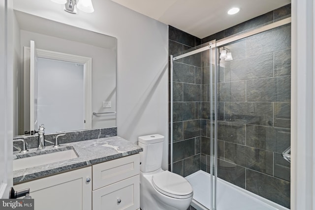 bathroom featuring vanity, a shower stall, and toilet