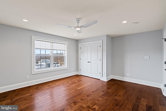 unfurnished bedroom featuring a closet, baseboards, dark wood-style flooring, and recessed lighting