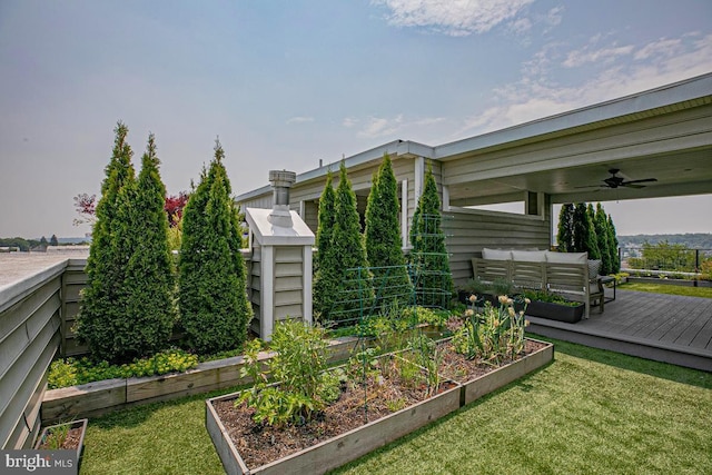 view of side of property with a yard, outdoor lounge area, a vegetable garden, and a ceiling fan